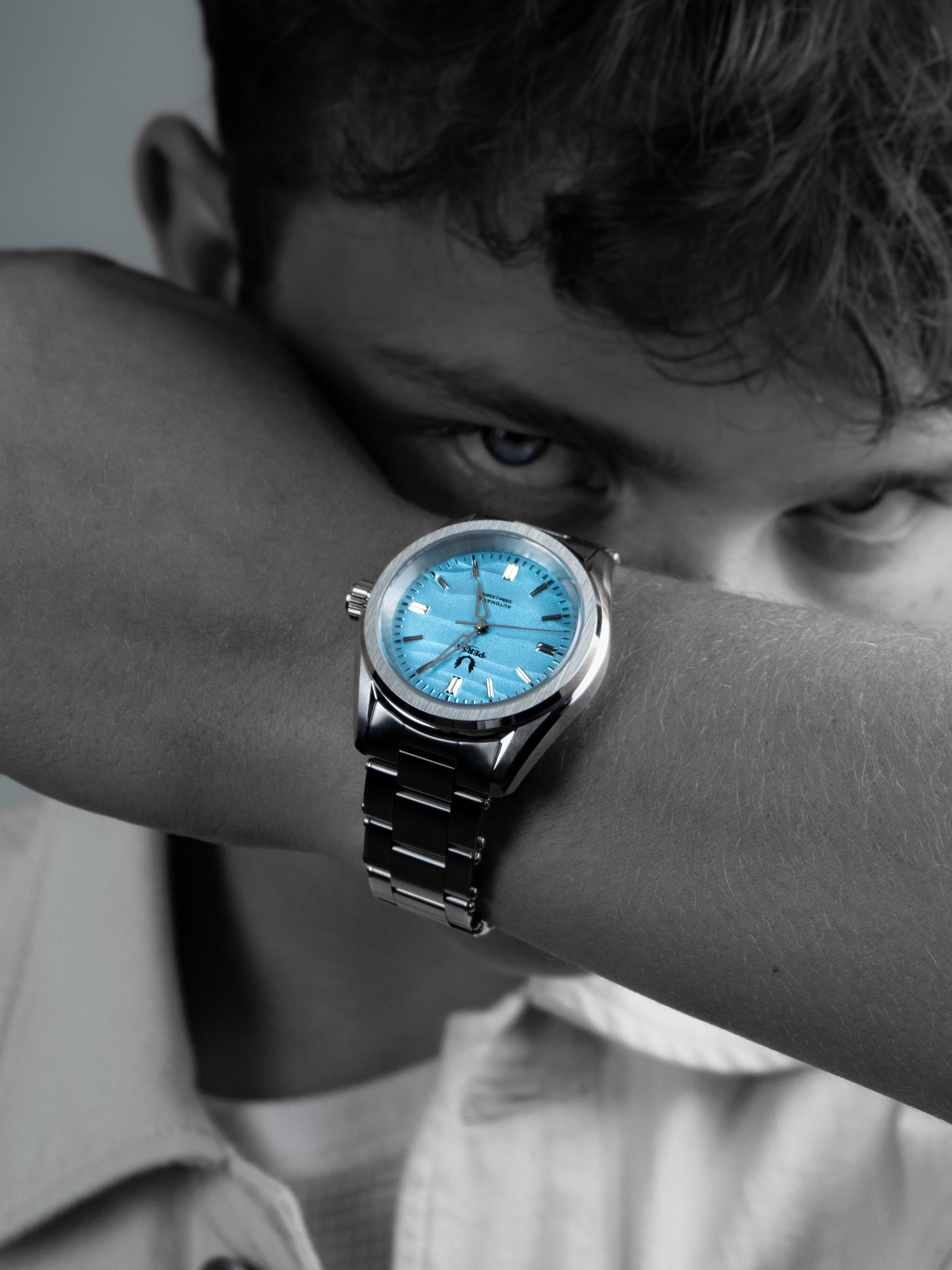 Azure blue dial automatic watch close-up on wrist in black and white portrait