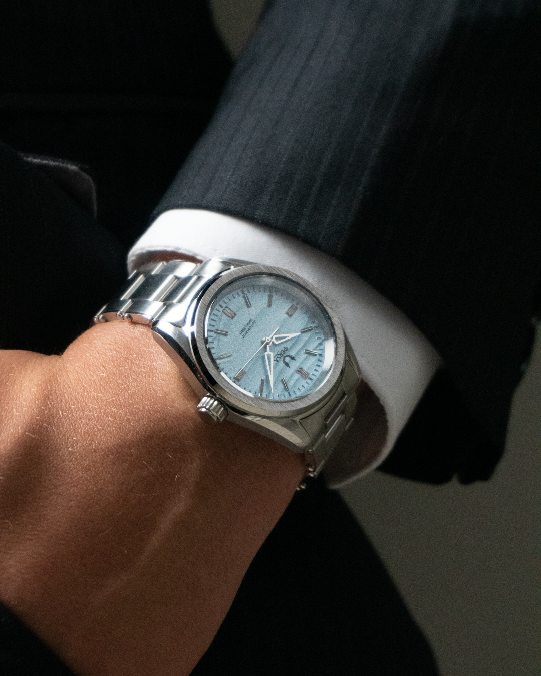 Azure blue dial automatic watch close-up on wrist in black and white portrait