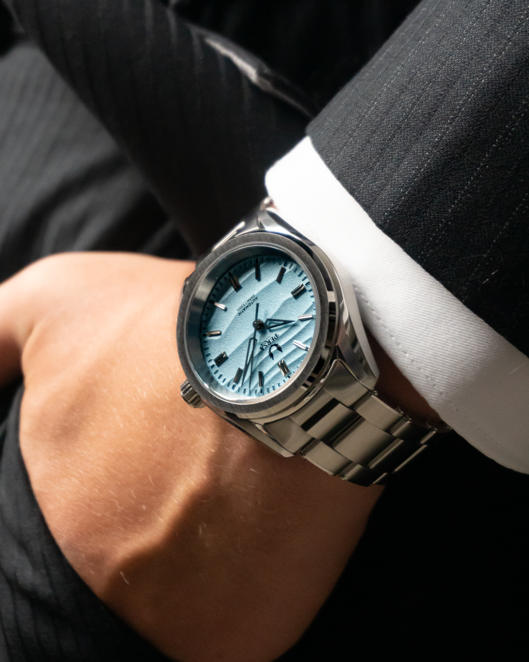 Azure blue dial automatic watch worn with a dark suit